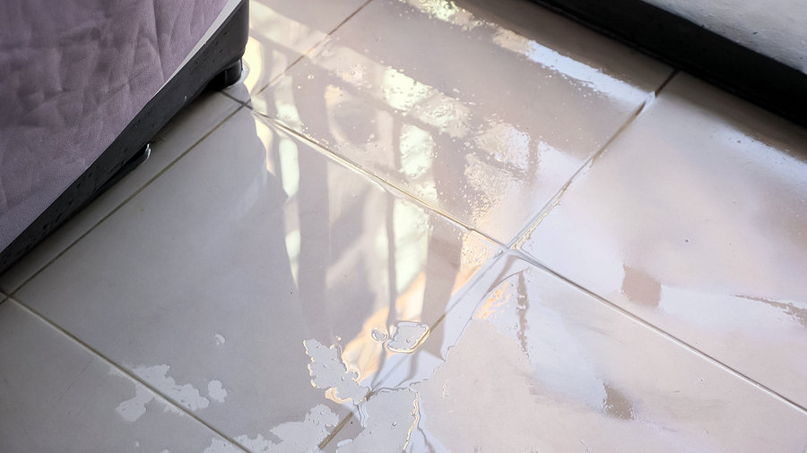 Trembling Water Puddle After Pipe Burst Covers White Tile Near F